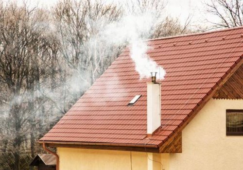casa con camino che fuma, la canna fumaria emette fumo bianco e grigio